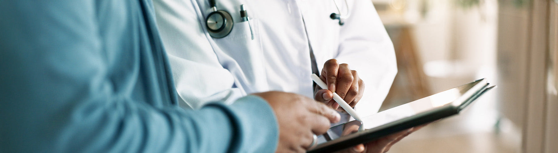 Doctor reviewing information on a tablet with a patient during a medical consultation.