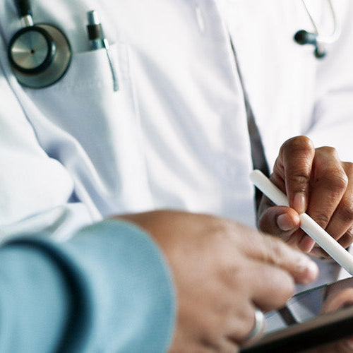 Doctor reviewing information on a tablet with a patient during a medical consultation.