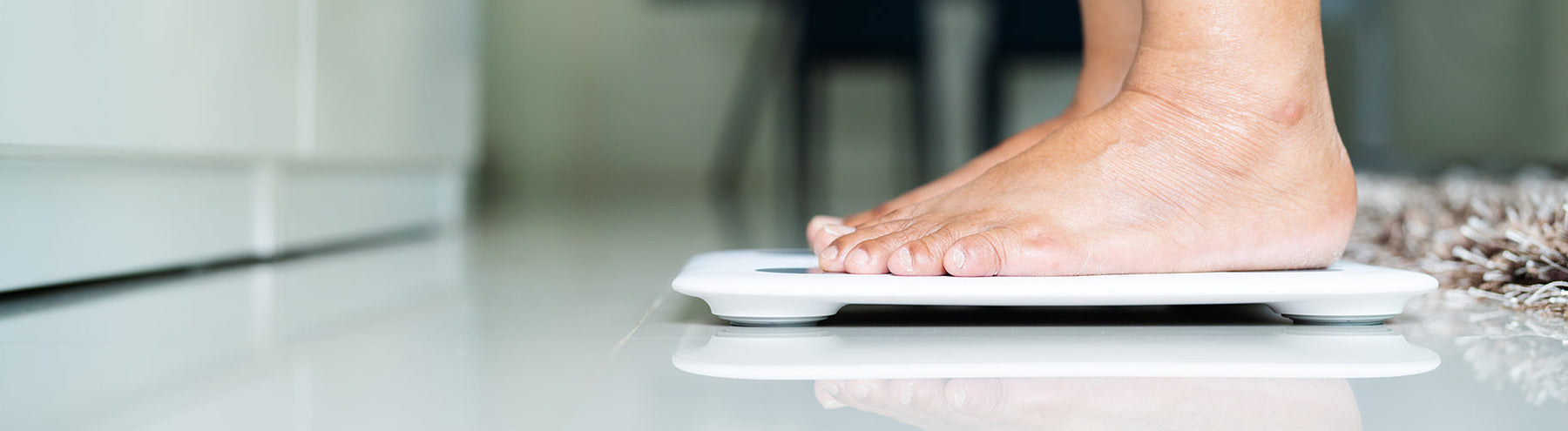 Woman standing on a digital bathroom scale to check body weight.