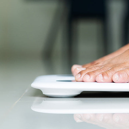 Woman standing on a digital bathroom scale to check body weight.