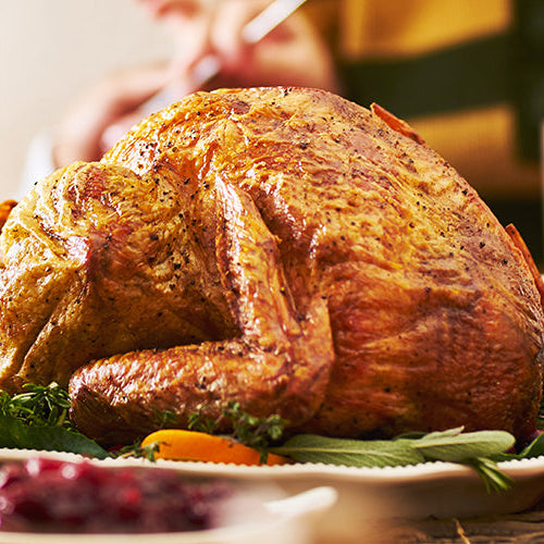 Thanksgiving dinner table with a roast turkey, mashed potatoes, cranberry sauce, and casserole.