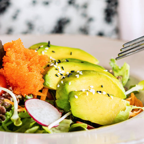 Fresh salad topped with avocado slices and vegetables.