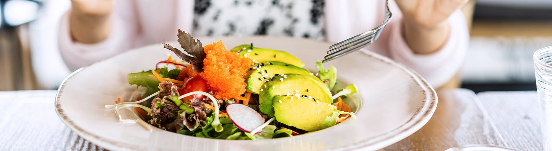 Fresh salad topped with avocado slices and vegetables.