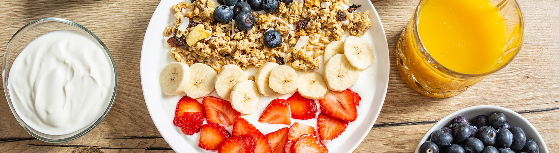 High-protein breakfast with granola, bananas, strawberries, blueberries and yogurt.