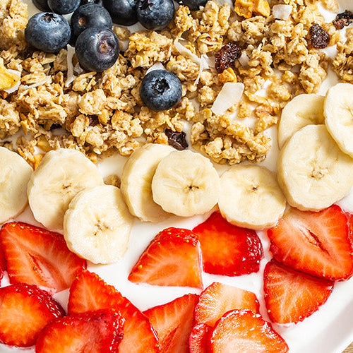 High-protein breakfast with granola, bananas, strawberries, blueberries and yogurt.