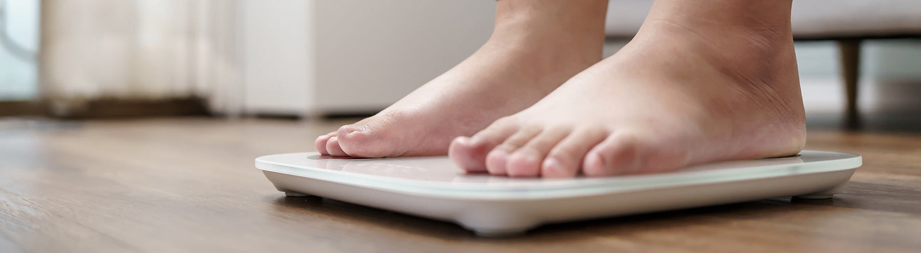 Close-up of a woman’s bare feet standing on a digital bathroom scale during.
