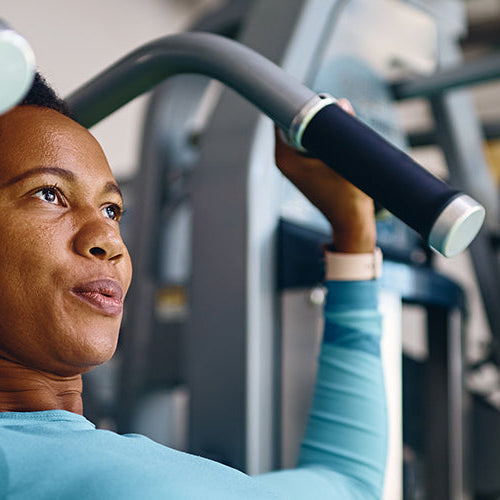 Woman strength training with a chest press machine at the gym.