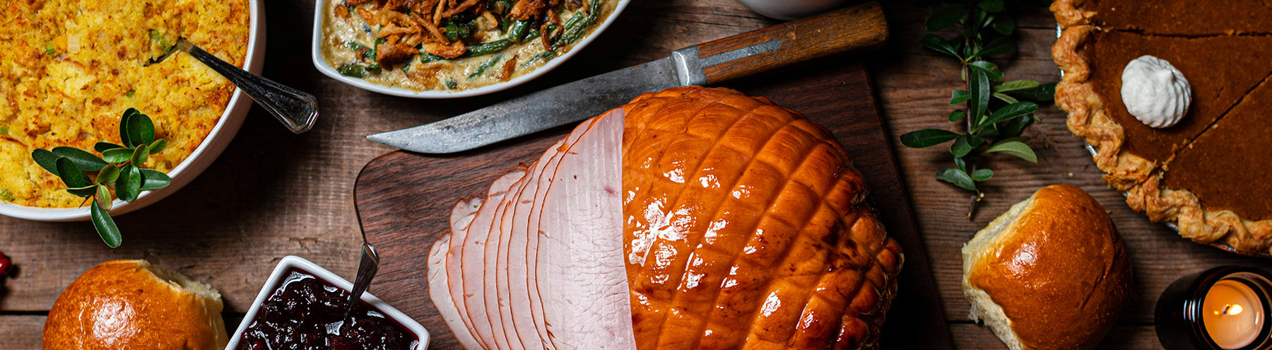 Assortment of holiday food on a table, including turkey, pumpkin pie, and casserole dish.