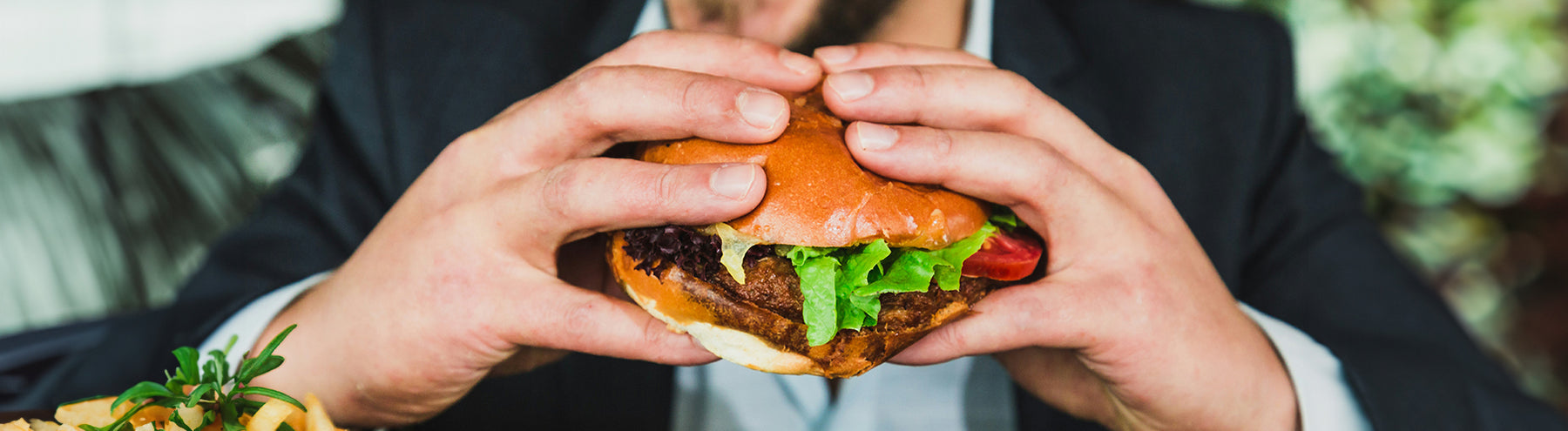 Man smiles as he holds up a burger to eat.