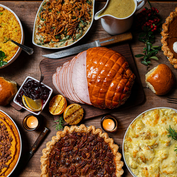 Assortment of holiday food on a table, including turkey, pumpkin pie, and casserole dish.