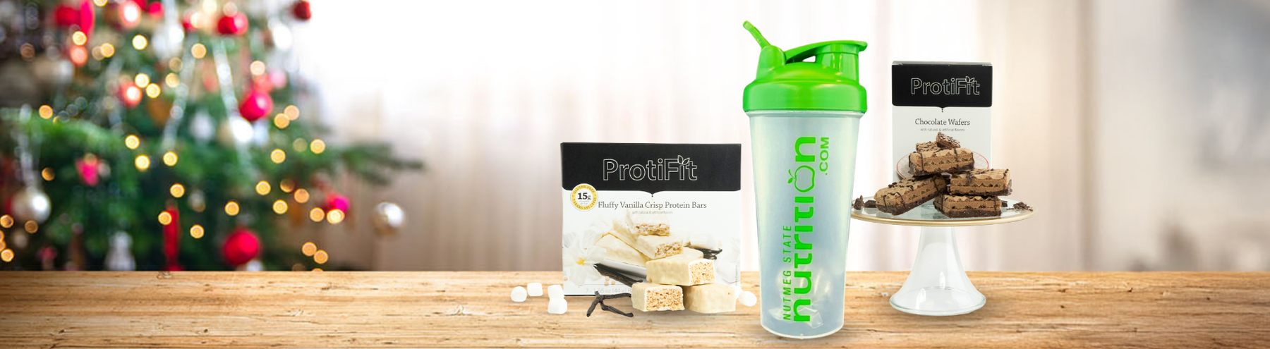Assortment of Proti Foods weight loss gifts with a Christmas tree in the background.